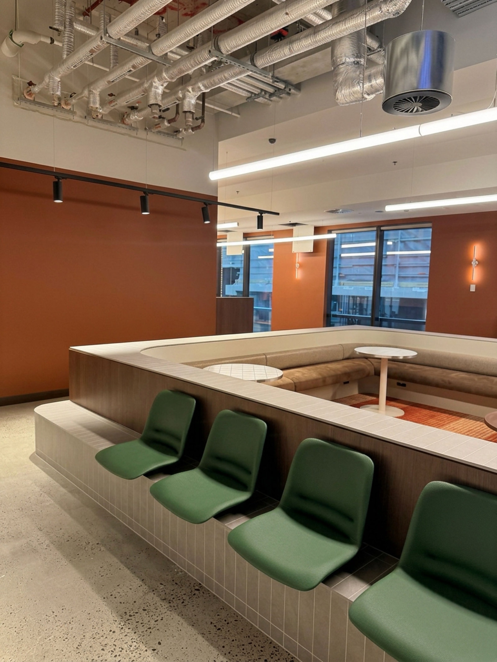Workplace breakout with terracotta walls and green seating